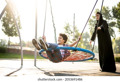 Cinematic image of a woman from the emirates with her children having fun at the playground - Powered by Shutterstock