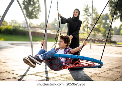 Cinematic image of a woman from the emirates with her children having fun at the playground - Powered by Shutterstock