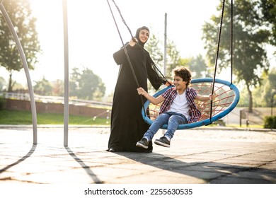 Cinematic image of a woman from the emirates with her children having fun at the playground - Powered by Shutterstock