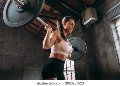 Cinematic Image Of A Young Woman Training In An Old Factory Style Gym In New York. Strong Female Athlete Training Hard With Sport Equipment As Ropes And Weights