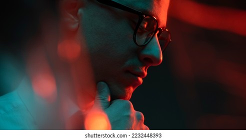 Cinematic night closeup portrait of handsome man neon lights. Concept of fashion, style, human emotions, facial expressions. Male fashion model wearing eyeglasses.