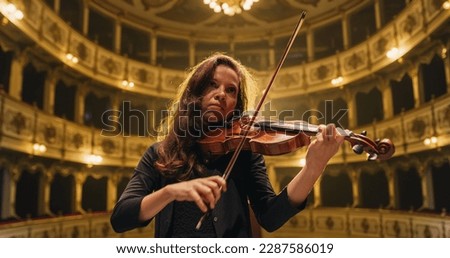 Cinematic Portrait of Female Violinist Playing Violin in an Orchestra Show on the Stage of a Classic Theatre. Musician Rehearsing for a Big Classical Music Concert