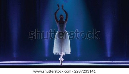 Cinematic Shot of Ballerina in Pointe Shoes and White Tutu Dancing and Rehearsing on Classic Theatre Stage with Dramatic Lighting. Graceful Classical Ballet Female Dancer Performing a Choreography