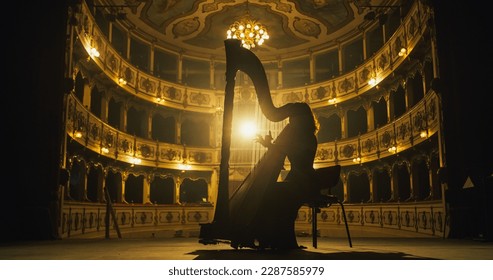 Cinematic shot of Female Harpist Playing Harp Solo on an Empty Classic Theatre Stage with Dramatic Lighting. Professional Musician Rehearsing Before the Start of a Big Show. Silhouette Aesthetics - Shutterstock ID 2287585979