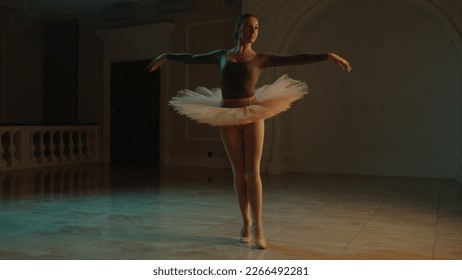 Cinematic shot of graceful female ballet dancer on choreography rehearsal in theater lobby, practicing elegant movements. Ballerina in tutu before performance in opera. Classical theatrical ballet art
