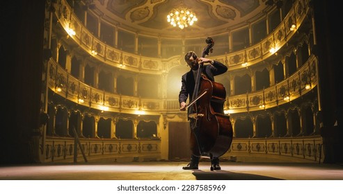 Cinematic shot of Male Cellist Playing Cello Solo on an Empty Classic Theatre Stage with Dramatic Lighting. Professional Musician Rehearsing Before the Start of a Big Show with Orchestra - Shutterstock ID 2287585969