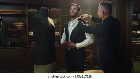 Cinematic Shot Of Professional Tailor Taking Measurements Of Client For Creation Custom Tailored Suit In A Luxury Tailoring Atelier. Concept Of Fashion, Handmade, Hand Craft, Couturier And Business