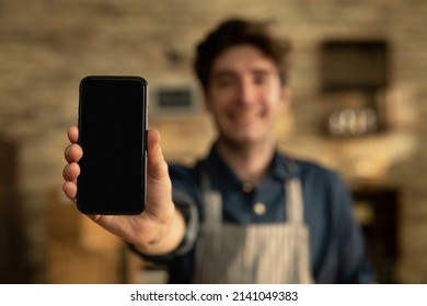 Cinematic shot of smiling artisan baker is showing in camera smartphone for online commerce applications for checking customer service and selling orders summary of baked goods in bakery shop. - Powered by Shutterstock