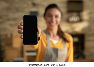 Cinematic shot of smiling female artisan baker is showing in camera smartphone for online commerce applications for checking customer service and selling orders summary of baked goods in bakery shop. - Powered by Shutterstock