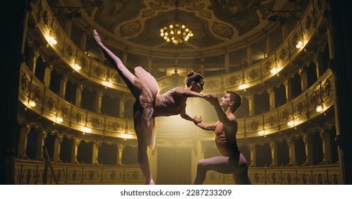 Cinematic shot of Two Young Classical Ballet Dancers Performing on Theatre Stage with Dramatic Lighting. Professional Male and Female Performers Rehearse their Choreography Together Before the show - Powered by Shutterstock