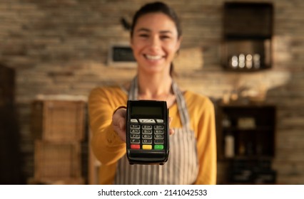 Cinematic shot of young friendly smiling saleswoman showing in camera atm terminal for contactless payments and NFC technology service in bakery shop. - Powered by Shutterstock