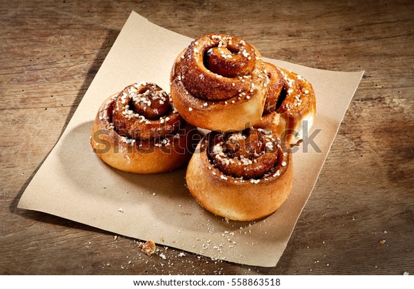 Cinnamon buns over a\
paper sheet on wood