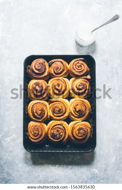Cinnamon rolls\
ready to be eaten for christmas holiday, top view over a gray\
background with a cup with sugar\
icing