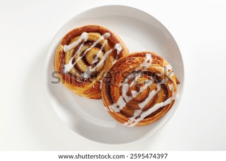 Cinnamon rolls scroll with icing on a plate on white background, top view