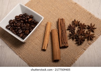 Cinnamon, Star Anise, Coffee Beans Up Close On A Hessian Cloth With A Light Wood Background Shot From Above