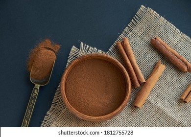 cinnamon sticks, tied with jute rope in rustic style. Ground cinnamon in a wooden bowl and vintage scoop. Close up on a black background. copy space for text. Top view, flat lay. - Powered by Shutterstock