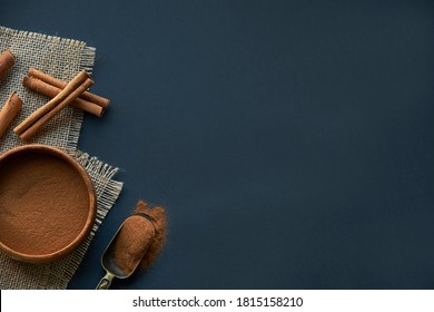 cinnamon sticks, tied with jute rope in rustic style. Ground cinnamon in a wooden bowl and vintage scoop. Close up on a black background. copy space for text. Top view, flat lay. - Powered by Shutterstock