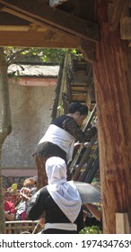 Ciptagelar, Indonesia - August 8 2019 : Asian Man Bring Bundle Of Rice Inside The Silo As Ceremonial Symbol Of The Harvest Festival Or Seren Taun