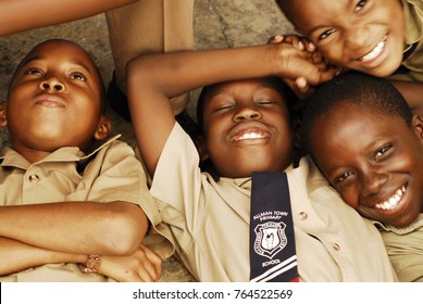 CIRCA 2010 Jamaica, Kingston, Close-up Portrait Of An African Schoolboy Lying Down With Eyes Closed Surrounded With Friends