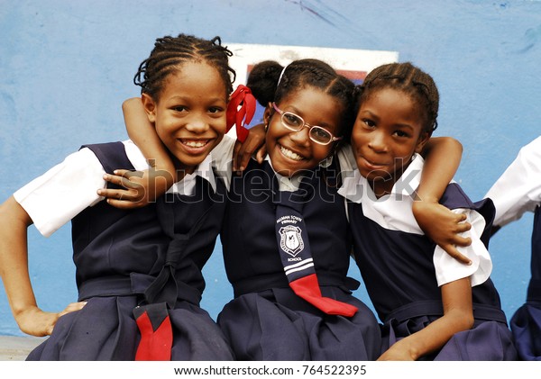 CIRCA 2010 Jamaica, Kingston,\
portrait of three African schoolgirls smiling with arm\
around