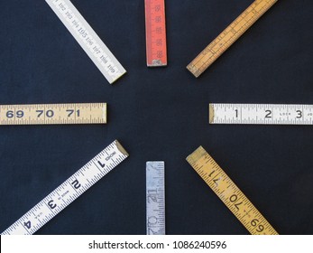 A Circle Arrangement Of Folding Rulers On Black Limbo Suggests Concepts Of Measurement, Precision, Accuracy, With Center Copy Space.