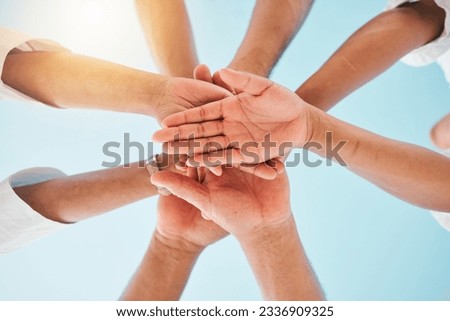 Circle, low angle and team with hands together for collaboration, unity or support by a blue sky. Teamwork, diversity and group of people in an outdoor huddle for motivation, solidarity or community.
