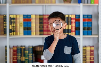 Circle Magnifying Glass Tightly Grabbed By Genius Asian Boy For Studying Funny Knowledge Of Scientific Observation, Physic Research, Light, Lens, Image Enlargement In Library Of Elementary School