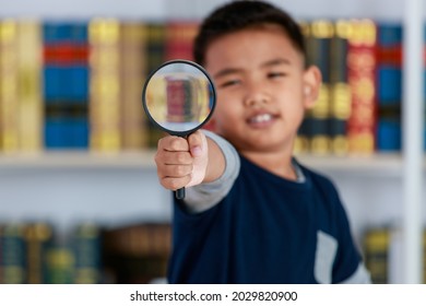 Circle Magnifying Glass Tightly Grabbed By Genius Asian Boy For Studying Funny Knowledge Of Scientific Observation, Physic Research, Light, Lens, Image Enlargement In Library Of Elementary School