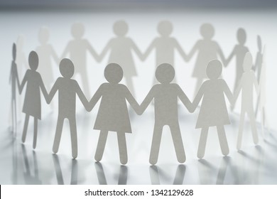 Circle of paper people holding hands on white surface. Community, brotherhood concept. Society and support. - Shutterstock ID 1342129628