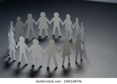 Circle of paper people holding hands on dark surface. Community, brotherhood concept. Society and support. - Shutterstock ID 1346148746
