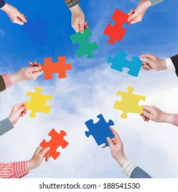 circle of people hands with different puzzle pieces with blue sky and white cloud background - Shutterstock ID 188541530
