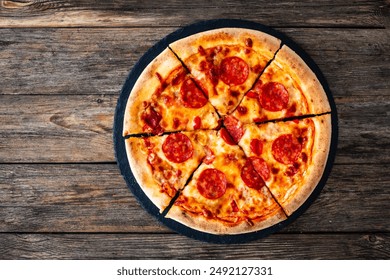 Circle pizza chorizo and mozzarella served on stony black plate on wooden table. Top view  - Powered by Shutterstock