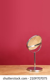 The circle shaped mirror setting on the desl with color background.