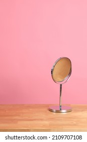 The circle shaped mirror setting on the desl with color background.
