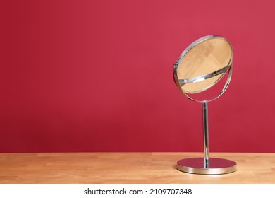 The circle shaped mirror setting on the desl with color background.