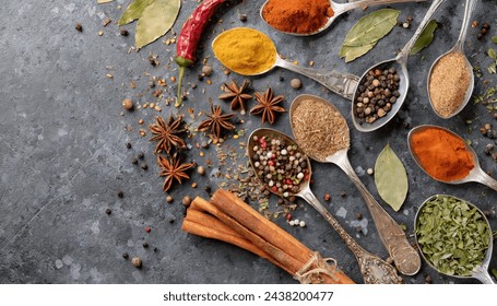 A circle of wooden spoons holding an array of assorted spices rests on a rustic stone tabletop. This vibrant display resembles an exotic Oriental spice market, brimming with colorful herbs and season. - Powered by Shutterstock