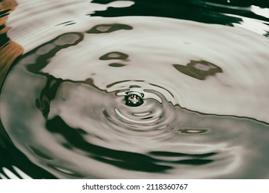 Circles On Dark Shiny Dirty Water With A Bubble In The Middle. Liquid Surface Background Banner In Shades Of Rust. View From Above. Provides Space For Text. Backdrop