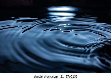 Circles On Dark Water Close-up. Reflection Of The Moon At Night On A Living Surface.