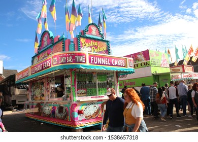 Circleville, Ohio-USA October 19,2019:
Annual Pumpkin Festival Yields Thousands Of Visitors For Food, Rides, Entertainment And All Things Pumpkin. Couple Passing By The Funnel Cake/Elephant Ears Stand