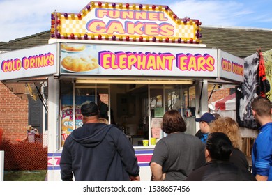 Circleville, Ohio-USA October 19,2019:
Annual Pumpkin Festival Yields Thousands Of Visitors For Food, Rides, Entertainment And All Things Pumpkin. Couple Passing By The Funnel Cake/Elephant Ears Stand