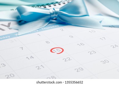 circling the date of the 15th day in the calendar. Concept of fertility chart, trying to have baby, Reminder Ovulation in graph, Planning of pregnancy. Blue bow.