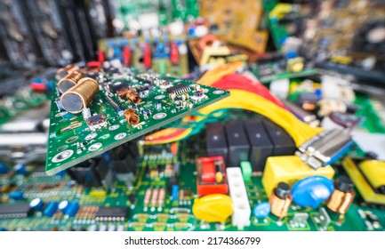 Circuit board on blur e-waste pile of discarded electric and computer devices. Air or ferrite core coils, chips or small components on cable TV amp PCB detail. Waste recycling in electronics industry. - Shutterstock ID 2174366799