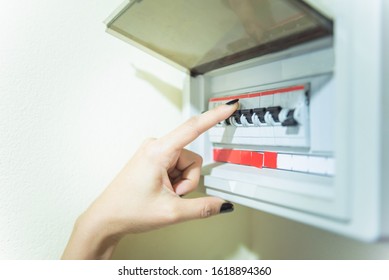 Circuit Breaker Board Displays Many Switches. A Finger Of Woman Is Turning It Back Off.