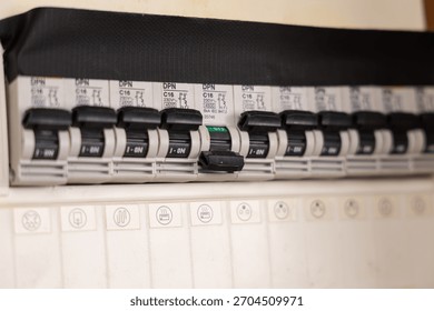 Circuit breakers in an electrical panel with one circuit breaker switched off.
