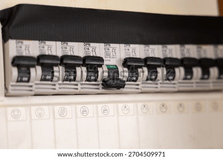 Circuit breakers in an electrical panel with one circuit breaker switched off.