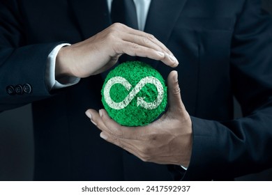 Circular economy concept. Hand of man holding green globe with a circular economy sign against dark background. Ideas for future growth of business and design to reuse and renewable material resource. - Powered by Shutterstock