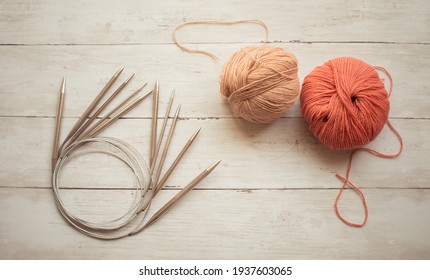 Circular knitting needles and beige, rust color wool yarn on the wooden background