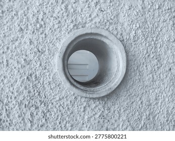A circular opening or pipe set into a heavily textured white wall, creating a minimalist geometric focal point.