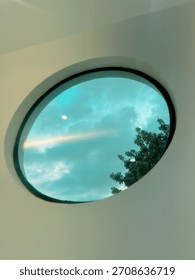 A circular skylight frames the blue sky and soft clouds like a natural painting.