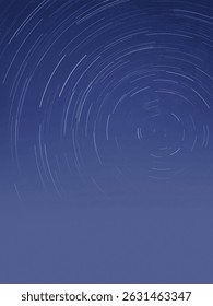 Circular star trails in a deep blue night sky, captured in long exposure photography showcasing Earth's rotation over time.